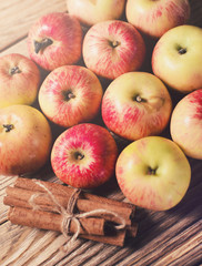 Ripe apples with cinnamon on wooden background
