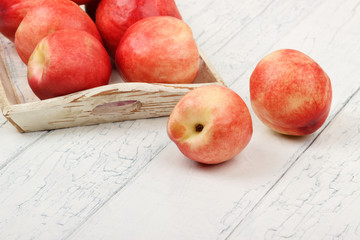 Ripe red peaches in the tray on the white wooden table