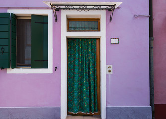 Beautiful colorful house facade on Burano island, north Italy. Purple wall with a door and a window