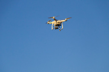 Quadcopter drone with the camera hovering in blue sky