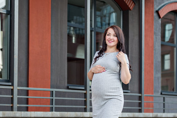  a young pregnant woman walking dancing along the city windows