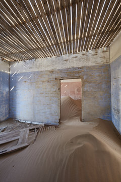 A view of a room in a derelict building full of sand.