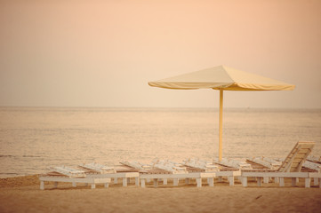 white chaise lounges and umbrellas at the sea during sunset, romantic time