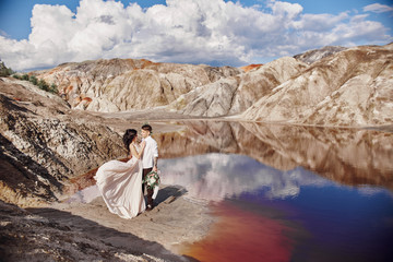 Couple in love hugging against the background of mountains and red lake. Unrealistic fairy-tale...