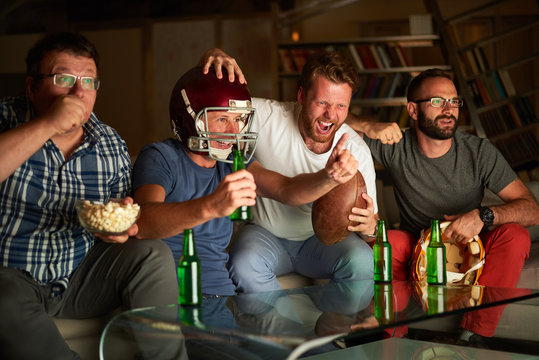 Four Friends Watching American Football Game On Television