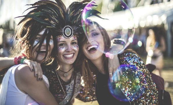 Three Young Women At Summer Music Festival Wearing Feather Headdress