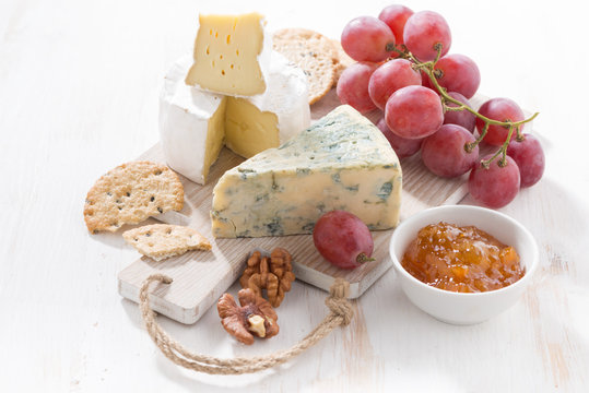 molded cheeses, fruit and snacks on a white wooden board