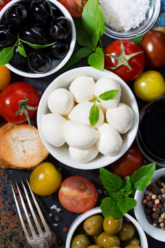 mozzarella, fresh ingredients for the salad and bread, vertical top view, closeup