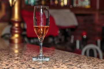 unfinished wineglass of rose wine on a high leg stand the bar made of marble