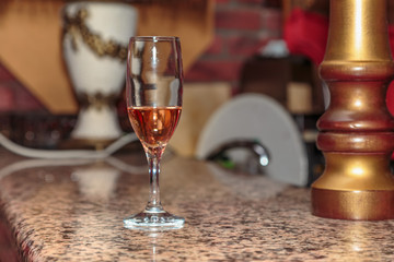 unfinished wineglass of rose wine on a high leg stand the bar made of marble