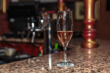 unfinished wineglass of rose wine on a high leg stand the bar made of marble
