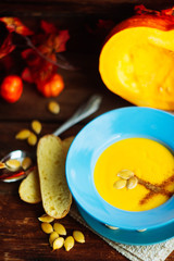 Pumpkin and carrot soup with cream and parsley on dark wooden background Top view