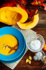 Pumpkin and carrot soup with cream and parsley on dark wooden background Top view