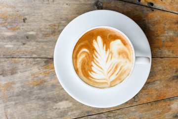 Coffee cup on old vintage wooden table with beautiful flower field background