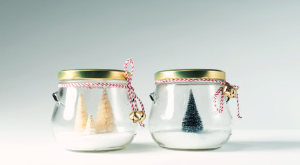 Small Christmas trees in glass jars on a white background