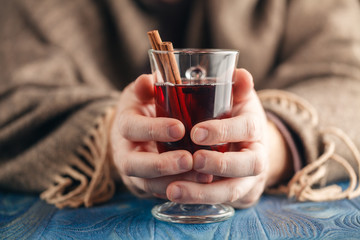 Hot alcohol drink, mulled wine with spices in male hand