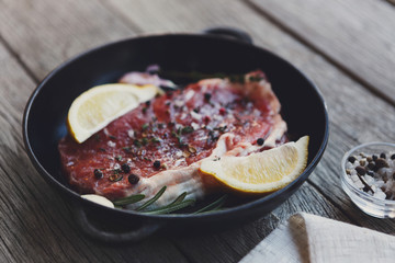 Raw beef steak with spices and herbs.