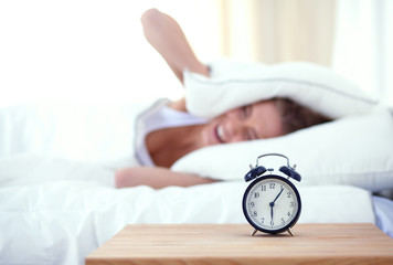 Young sleeping woman and alarm clock in bedroom at home. Young sleeping woman.