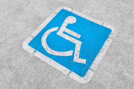 Blue disabled parking sign painted on dark asphalt in Canada in Ucluelet, Canada