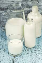 Jar and bottles with milk, and full glass with milk