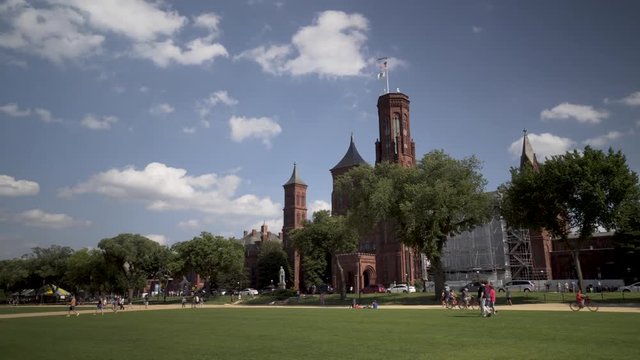 Steadicam shot walking towards the Smithsonian Institution Castle Museum on a beautiful late spring day with blue sky and white clouds.
