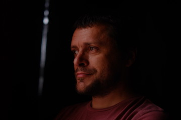 sad man on a dark background, photo in a low key