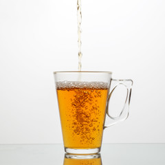 Pour tasty tea into a glass cup. The concept of dishes and drinks.