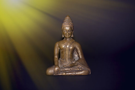 Buddhist meditation. Traditional bronze buddha meditating in rays of divine light. Zen buddhism and spiritual enlightenment or awakening.
