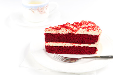 Red Velvet Cake sliced in piece on white plate with stainless fork on white background with cup of green tea for celebrate X'mas season occasion, Valentines day, birthday or special holiday events