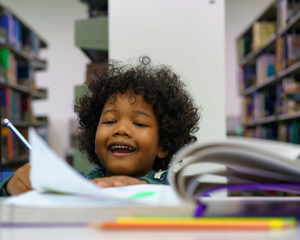 little boy reading book in the library