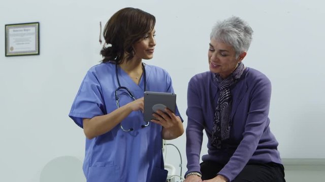 Young nurse speaking with patient using tablet