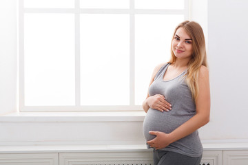 Smiling pregnant woman dreaming about child, copy space.