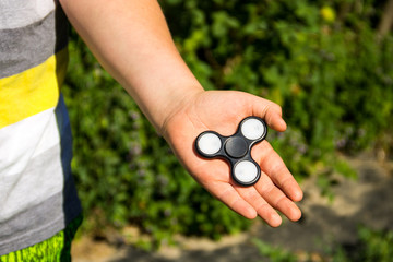 Boy playing with fidget spinner stress relieving toy outdoor