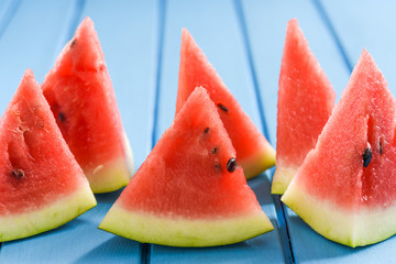 Fresh watermelon slices on blue background look like sails in sea