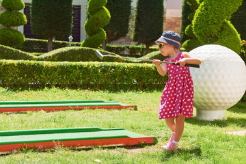 Child playing mini - golf on artificial grass.