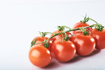 Branch of red organic tomatoes on a white background