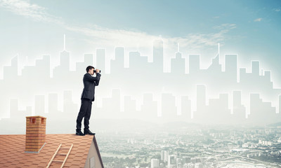 Businessman standing on roof and looking in binoculars. Mixed me