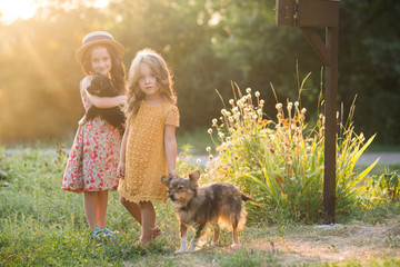 two little sisters walking in autumn park at sunset with dogs