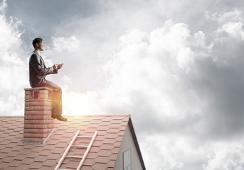 Student guy in suit on brick house roof reading book