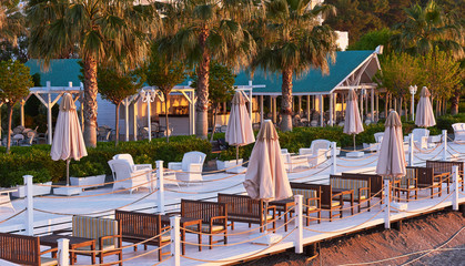 Scenic view of private sandy beach with sun beds and parasokamy the sea and mountains. Resort.
