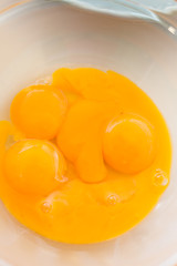 raw eggs without shell in a plate. bright yolk of chicken eggs