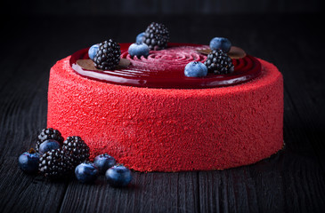 Delicious pink cake with berries on black wooden table