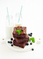 Chocolate brownies with blueberries and cream filling. Dark background.