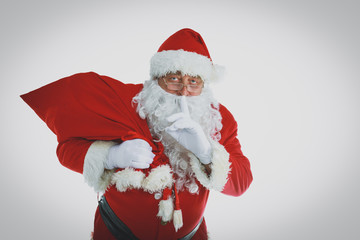 Real Santa Claus carrying big bag full of gifts, isolated on white background