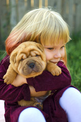 Little cute blond girl hugs shar pei puppy. Lovely friendship with pet