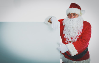 Happy Santa Claus looking out from behind the blank sign isolated on white background
