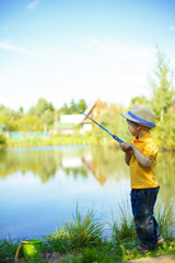 Little boy is engaged in fishing in a pond. Child with a dairy in his hands.