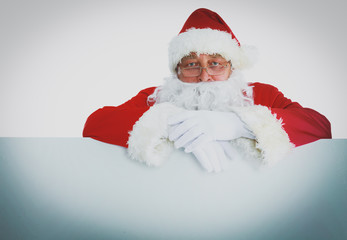 Happy Santa Claus looking out from behind the blank sign isolated on white background