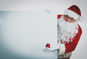 Happy Santa Claus looking out from behind the blank sign isolated on white background