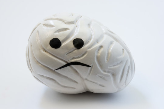 Concept photo of unhappy, sad brain with sickness disorder. Model of brain with sad smile, which symbolizes neurologic problem: discomfort, headache, ache, spasm, inflammation, migraine